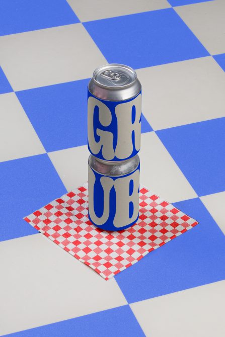 Product mockup featuring stacked cans with bold typography on a checkered surface, ideal for graphic design showcases.