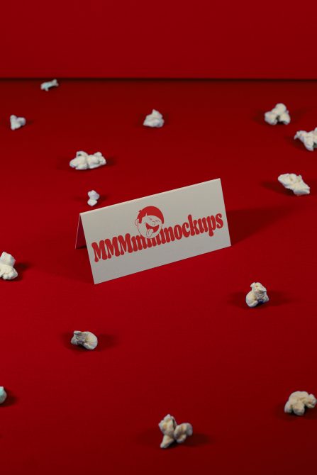 Creative business card mockup on red background with scattered popcorn, ideal for branding presentations and design showcases.