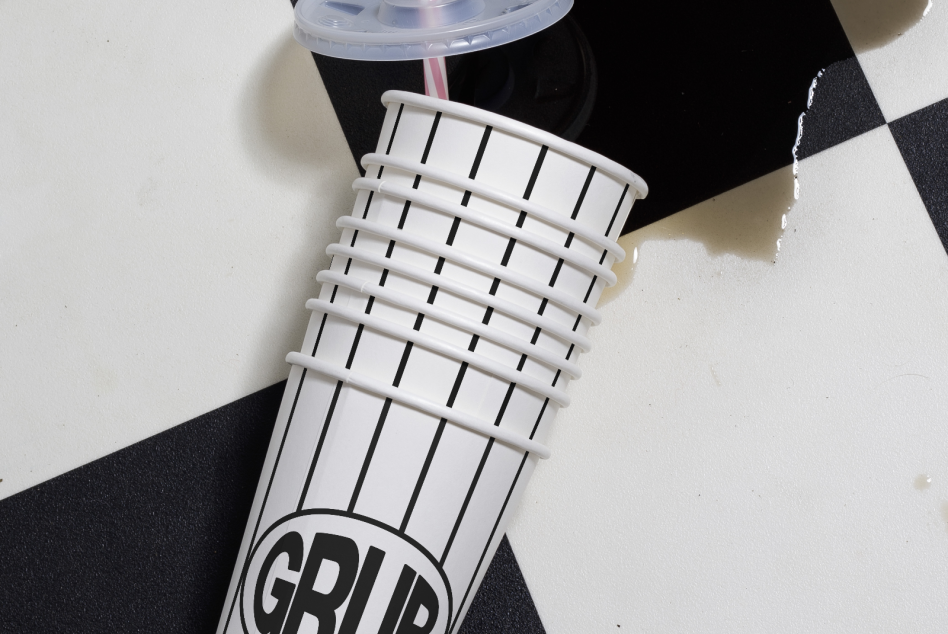 Stacked paper cups mockup with modern striped design on a checkered background, showcasing product presentation for designers.