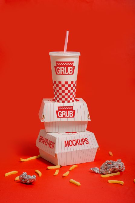 Vibrant fast-food packaging mockup with drink cup, boxes, and fries on red background, ideal for restaurant branding presentations.