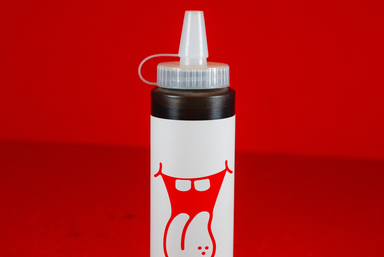 White glue bottle with red cap and printed smiley design isolated on red background, perfect for Mockups category, creative product display.