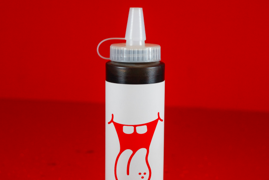 White glue bottle with red cap and printed smiley design isolated on red background, perfect for Mockups category, creative product display.