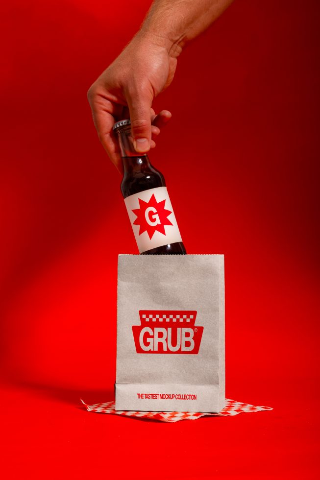 Hand holding branded beer bottle above paper bag on red background, mockup, packaging design, product presentation, beverage branding.