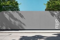 Concrete wall with colorful neon glow effect under bright blue sky with tree shadows
