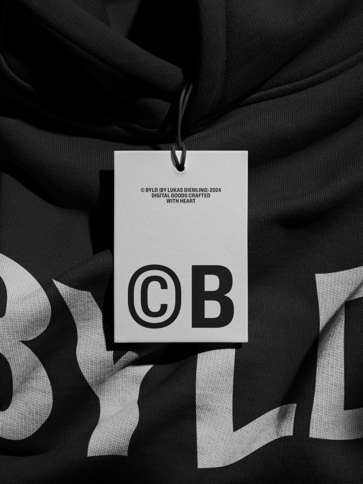 Clothing tag mockup with BYLD branding on crumpled black fabric with striped pattern