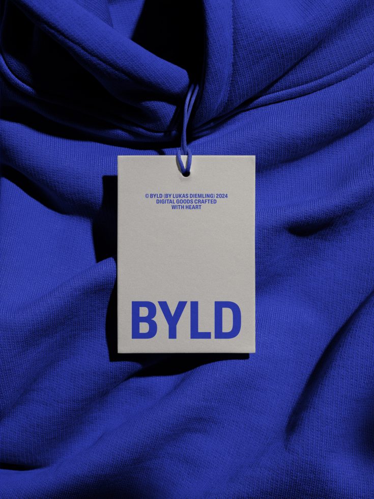 Cream hang tag with bold blue BYLD logo on crumpled royal blue fabric background
