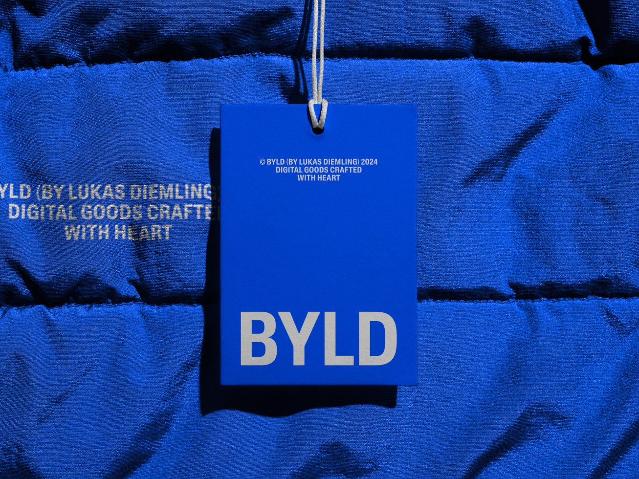 Blue tag mockup hanging on fabric with BYLD branding, ideal for designers to showcase logo design and branding in realistic settings.