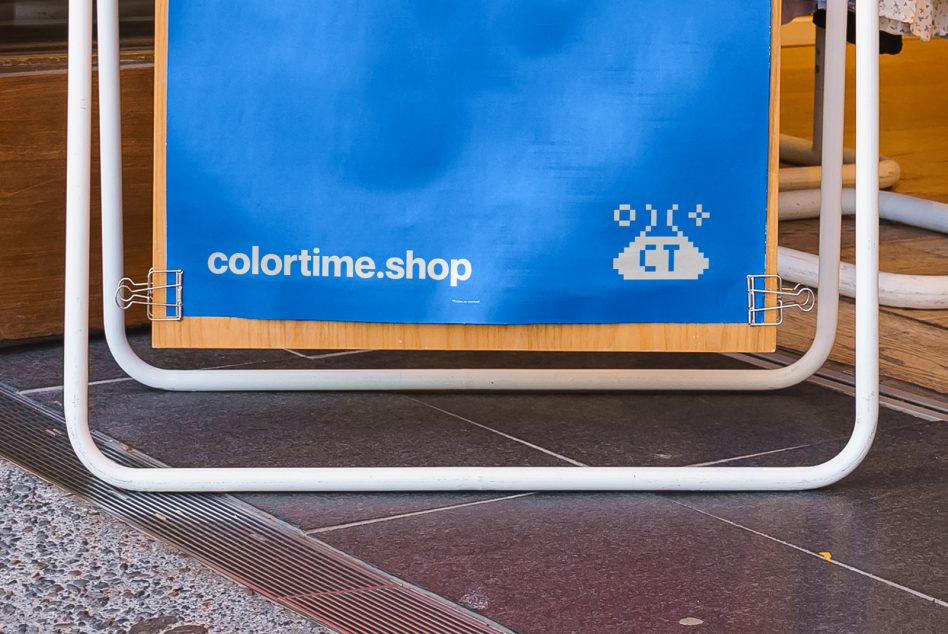 Bright blue sidewalk sign with white frame showing colortime.shop branding