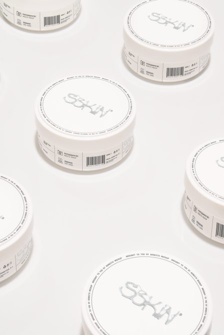 Multiple white cosmetic jars scattered overhead showing tops, sides, bases