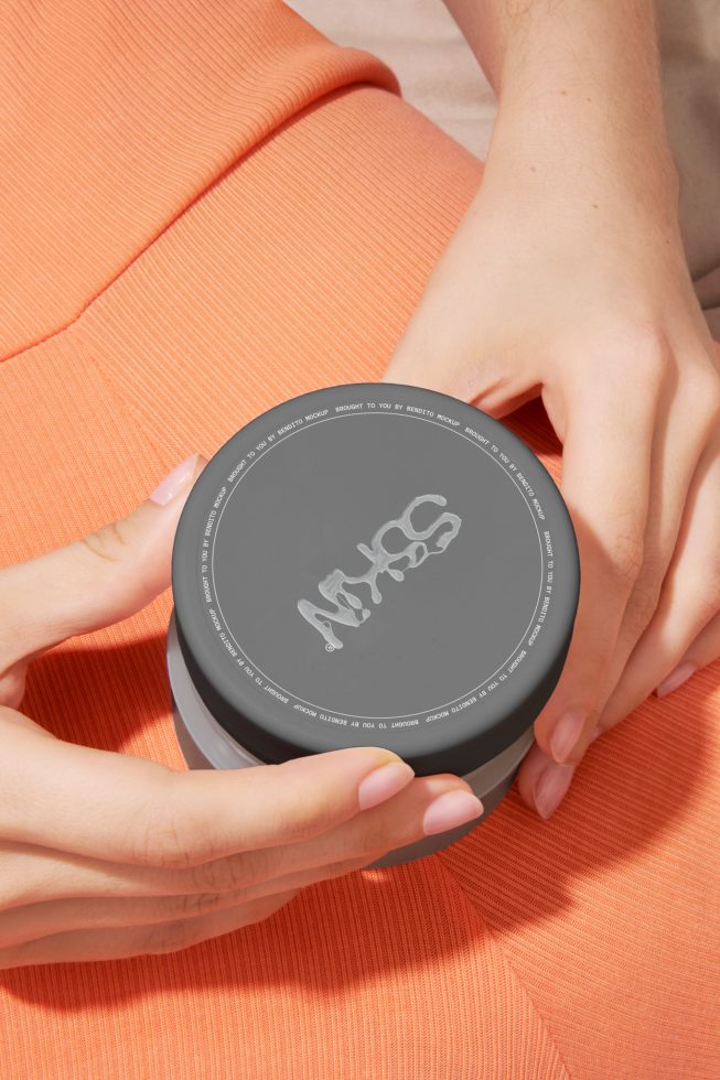 Hands holding cosmetic jar on fabric texture, ideal for beauty product mockups and packaging designs by designers and marketers.