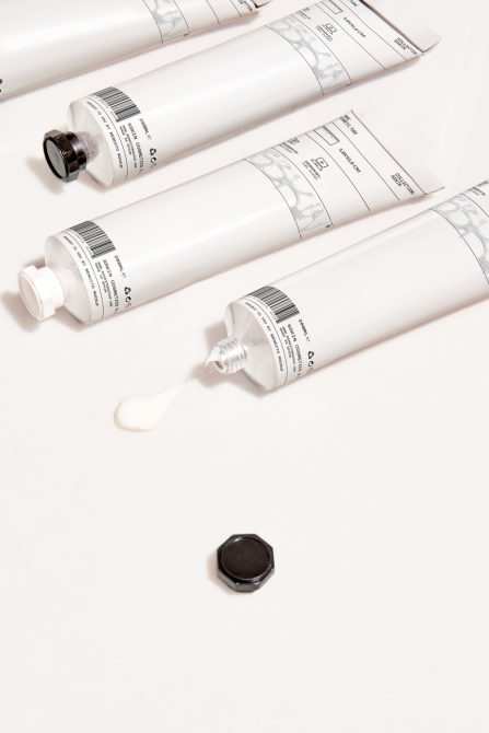 Cosmetic tube packaging mockup with selective focus, showing multiple white tubes partially squeezed with visible barcode, ideal for product design.