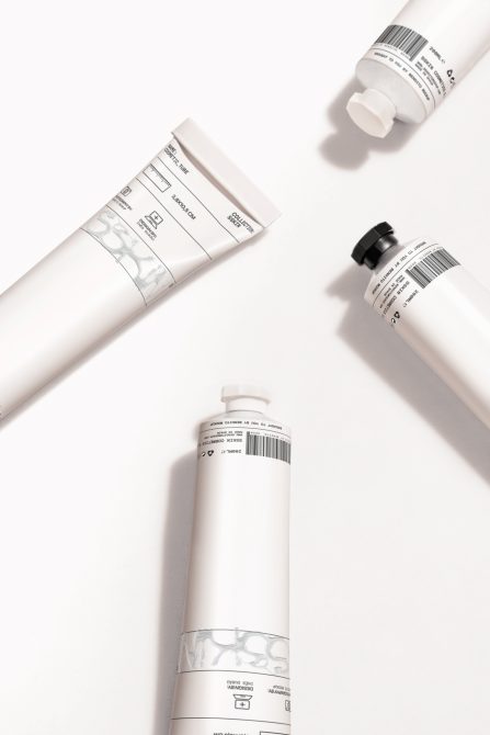 White cream tubes with black pump bottles casting soft shadows on minimalist surface