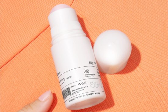 Cosmetic bottle mockup on orange fabric with female finger, beauty product packaging, skincare designer asset.