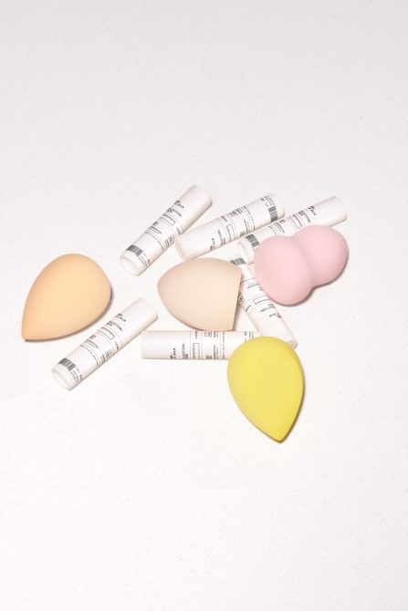 Makeup sponge set with white applicator bottles arranged in teardrop shapes overhead view