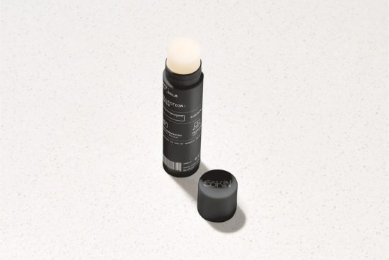 Cosmetic stick product mockup on a speckled background showcasing label design and packaging, ideal for beauty brand presentations.