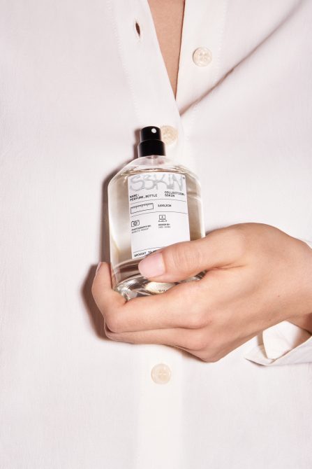 Person in white shirt holding perfume bottle with white label