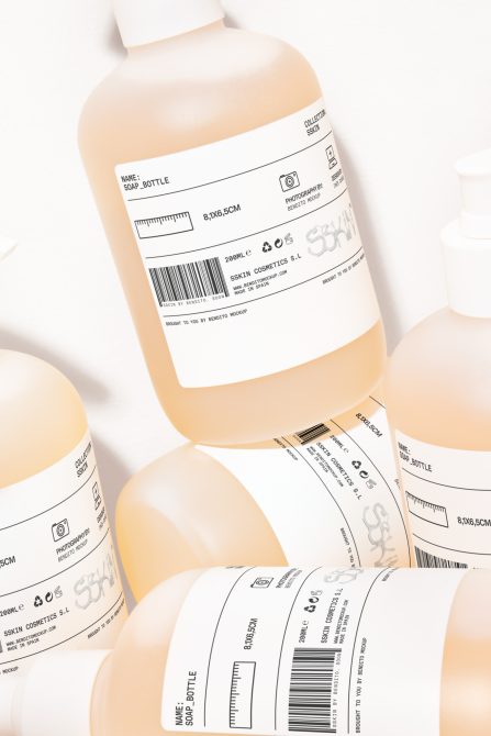 Group of peach colored bottles with label mockups, white black variant designs