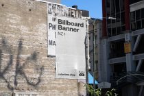 Light billboard banner mockup on textured brick building in city