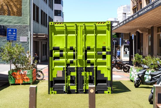 Bright green shipping container on urban street with pixelated camouflage pattern, ideal for graphics and mockups.