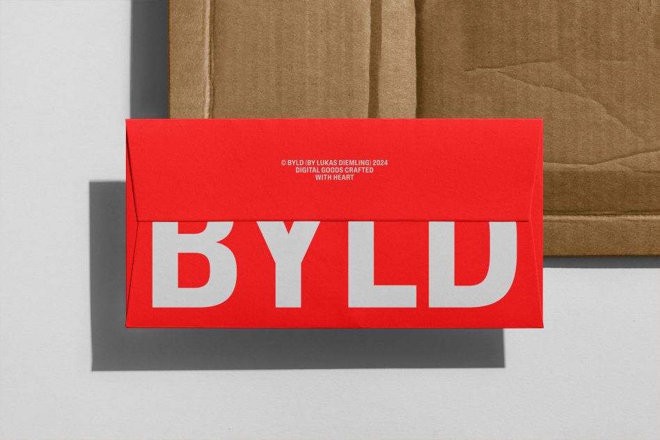 Bright red envelope mockup with bold white BYLD lettering, cast shadow on white surface, tan fabric backdrop