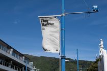 White flag banner mockup fluttering on blue pole with mountain backdrop