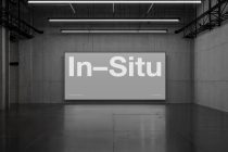 Industrial warehouse space with linear ceiling lights above a large horizontal display screen