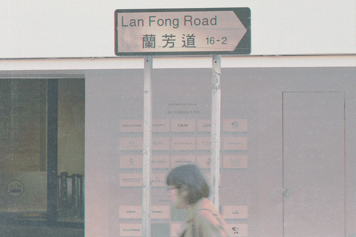 Vintage street sign Lan Fong Road with blurred person walking past textured background for graphics and templates