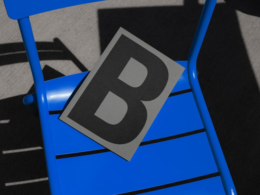 Bold letter B on paper card placed on a blue chair mockup, ideal for typography presentation in design projects.