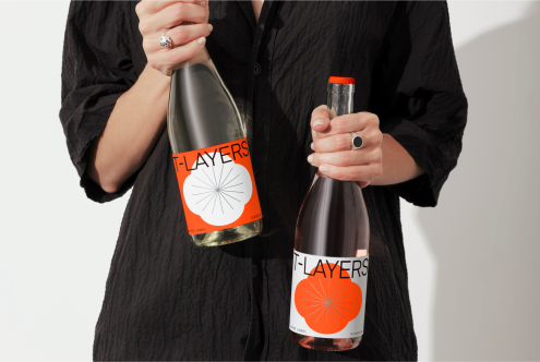 Person holding two bottles with modern labels, ideal for mockup template showcasing product branding and packaging design.