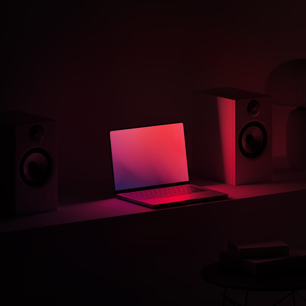 Stylish workspace mockup with open laptop on desk, red ambient lighting, speakers, lamp, and books for digital designers.