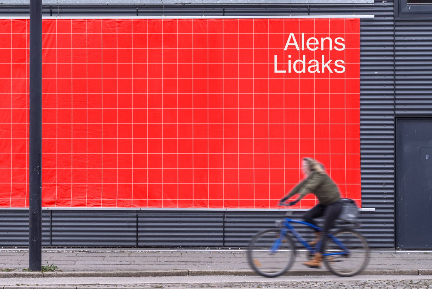 Large red billboard mockup with editable text area in urban setting with passing cyclist, perfect for outdoor advertising designs.