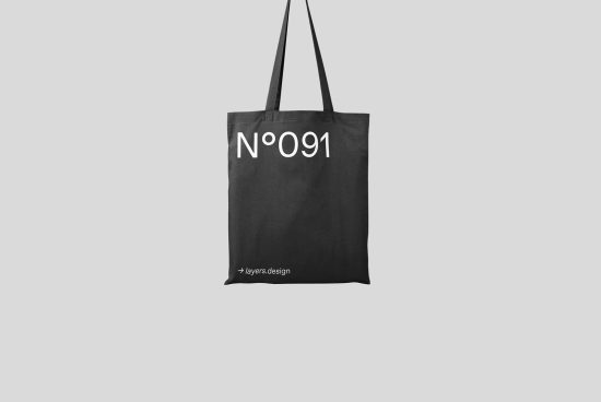 Black tote bag mockup with white typography design hanging against a plain background, perfect for presentations and portfolios.