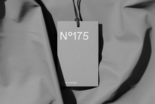 Elegant tag mockup hanging on black thread with monochrome fabric background, showcasing minimalist design for branding and packaging.