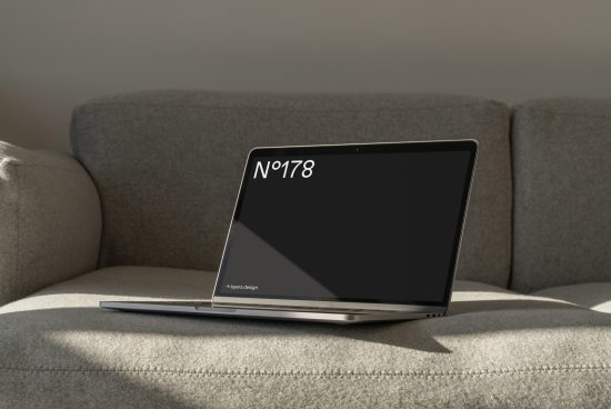 Laptop with blank screen on a sofa for website design mockup, natural lighting, modern minimalist setting, digital asset for designers.