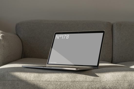 Laptop on sofa in sunlight for website template mockup, modern design, realistic setting, digital asset for designers, downloadable showcase template.