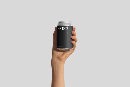 Hand holding a sleek black soda can mockup with minimalistic design against a neutral background, ideal for branding presentations.