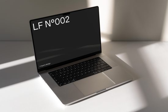 Elegant laptop mockup on desk with soft shadows, showcasing typography design on screen, ideal for digital asset presentations.