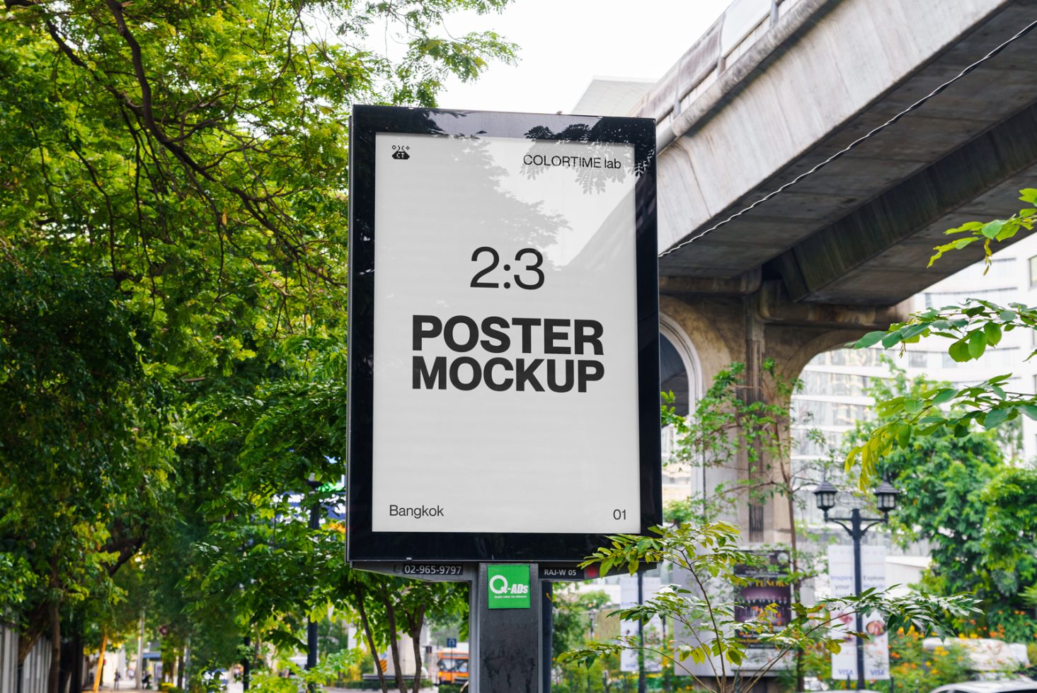 Urban outdoor poster mockup hanging on a street pole with green trees and city architecture in the background. Ideal for realistic design presentations.