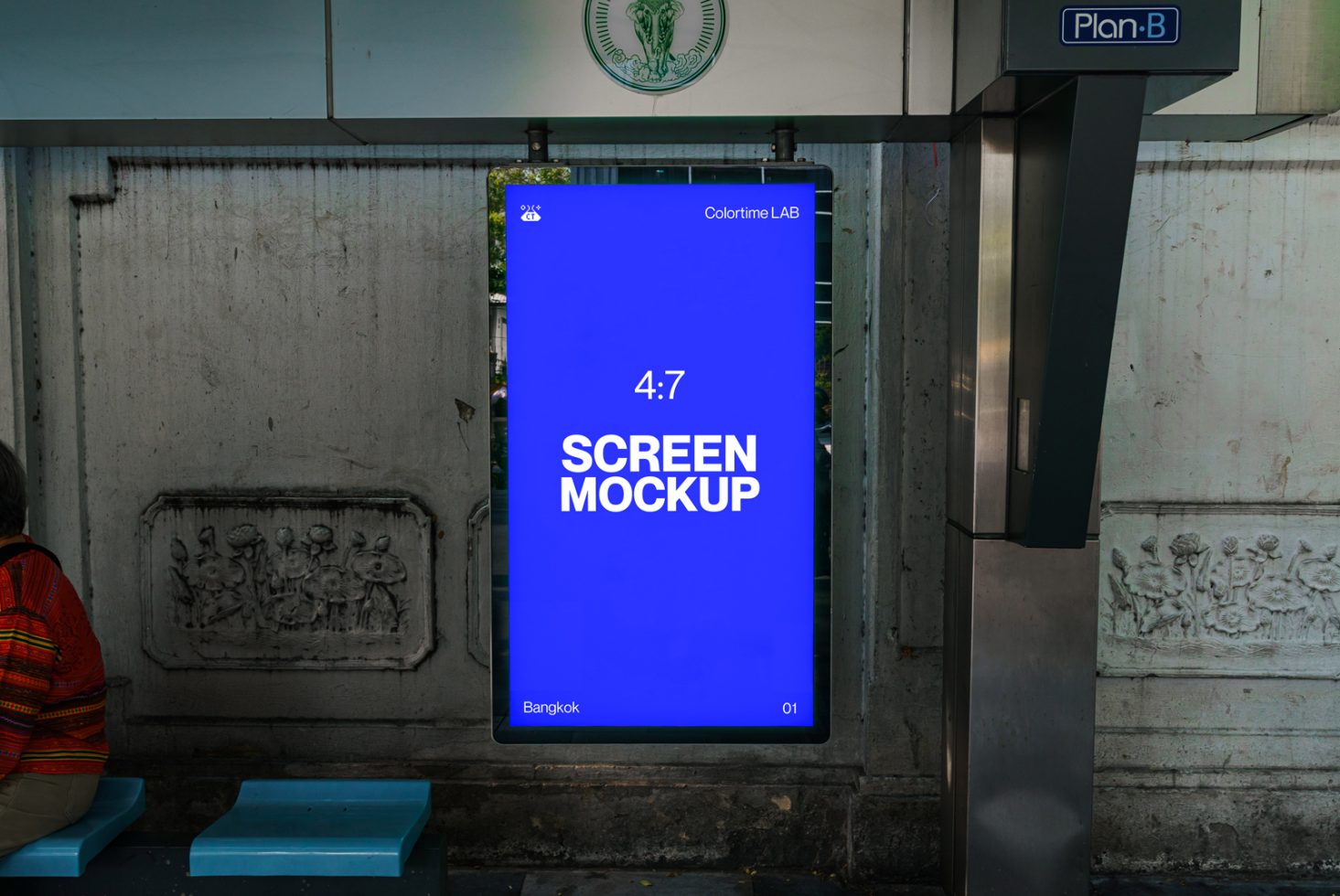 Urban digital billboard screen mockup in an outdoor setting with a person sitting nearby, perfect for designers to showcase ads.