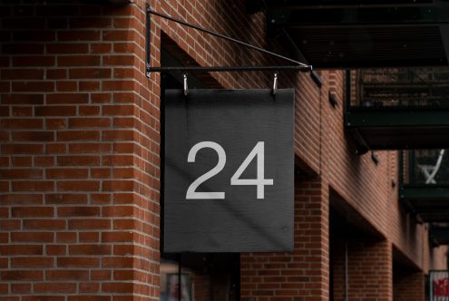 Rustic street number sign mockup on brick wall, urban setting ideal for presenting address fonts and exterior signage designs for businesses.