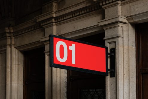 Red and white numbered signboard mockup hanging on a classic building, perfect for storefront branding design presentations.