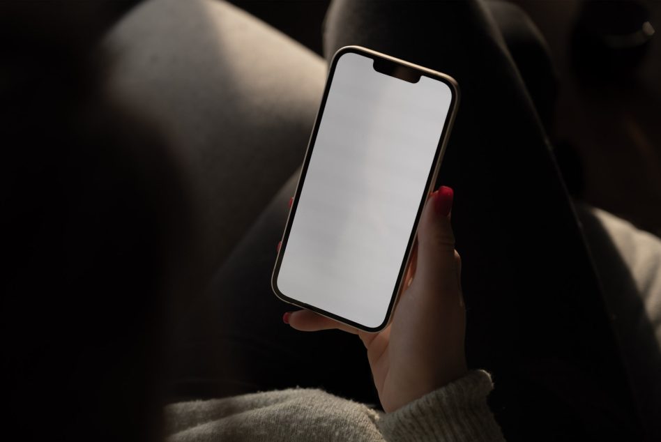 Person holding smartphone with blank screen, ideal for mockup, in a natural light setting, showcasing device display design space.