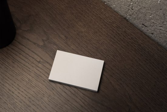 Blank business card mockup on a wooden table with soft lighting, realistic shadows, ideal for branding design presentation.