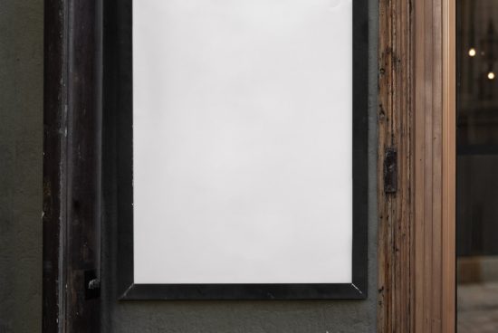 Blank vertical poster mockup in a metal frame on a street wall, ideal for designers' branding projects and ads display.