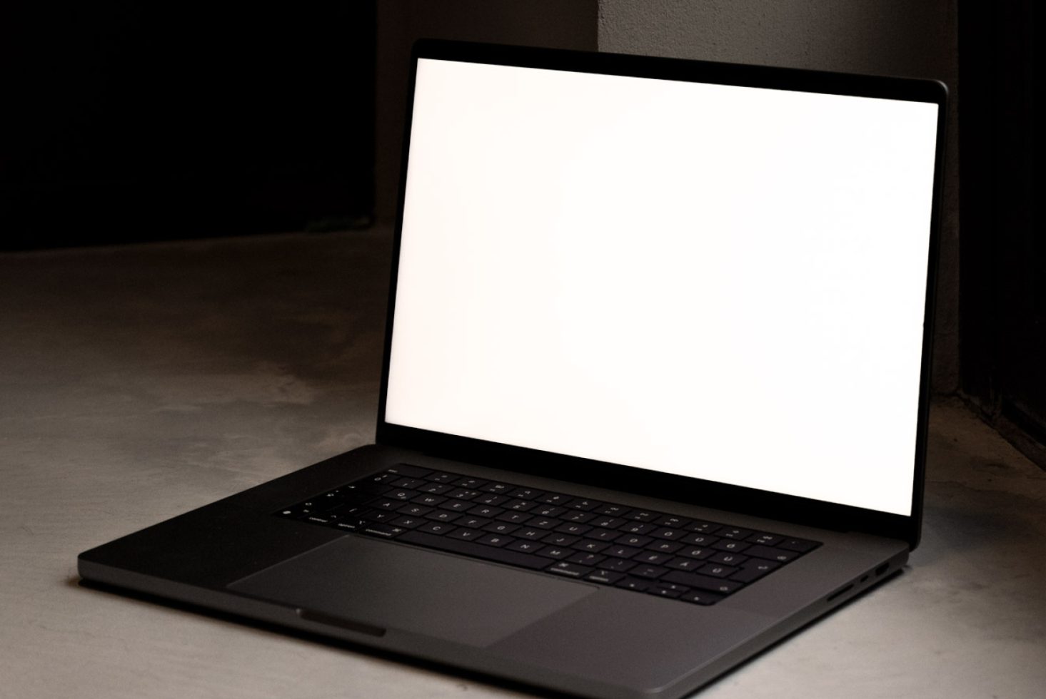 Laptop mockup on a dark surface with a blank screen, ideal for showcasing web designs and applications, perfect for designers.