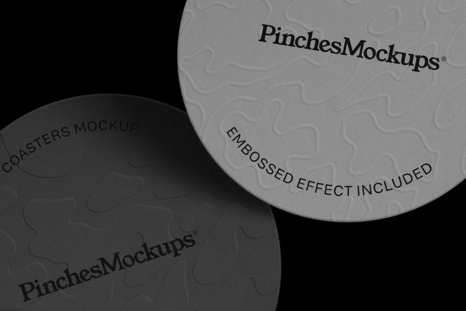 Two round coasters with embossed branding, one dark one light, showing textured surface details against black background