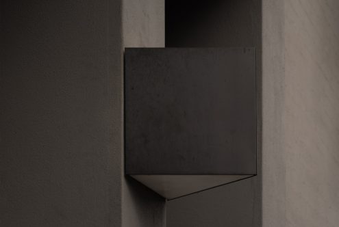 Minimalist geometric wall light fixture in a dimly lit modern setting, perfect for mockup use in interior design projects.