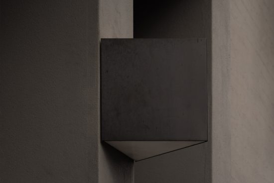 Minimalist geometric wall light fixture in a dimly lit modern setting, perfect for mockup use in interior design projects.