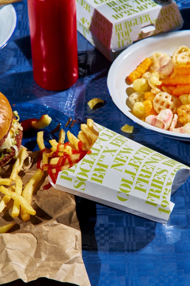 Fast food mockup with burger, fries packaging, and condiments on a blue surface for food-related graphics and templates design.