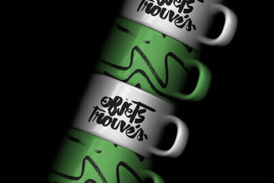 Angled stacked mugs with green stripes, script branding on white ceramic